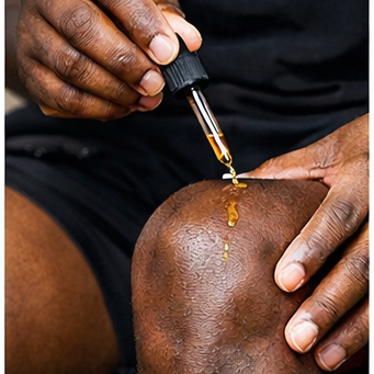 Person applying a dropper of oil to their knee
